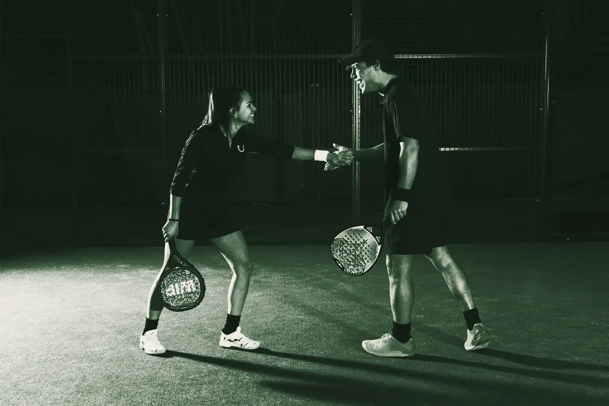 Two players shake hands at the net on a blue court